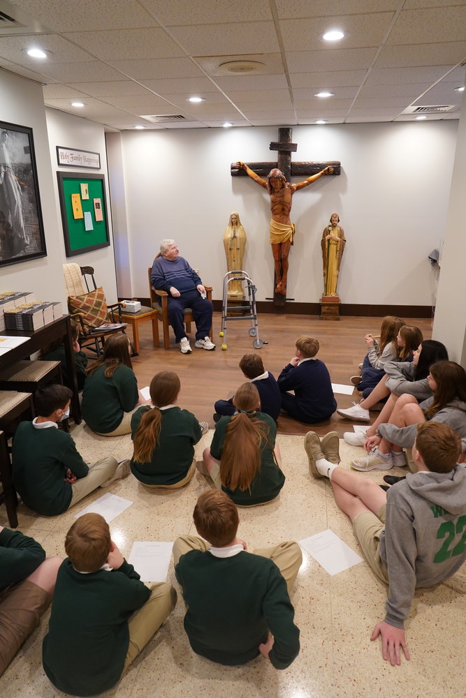 Artist Delbert Hayes tells students of Holy Family School in Hannibal about the crucifix he created about 20 years ago for Holy Family Church. They met with him March 10 in what is not the gathering area for the church.